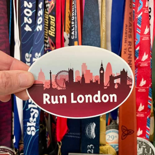Sticker with 'Run London' text held over a collection of colorful race medals.