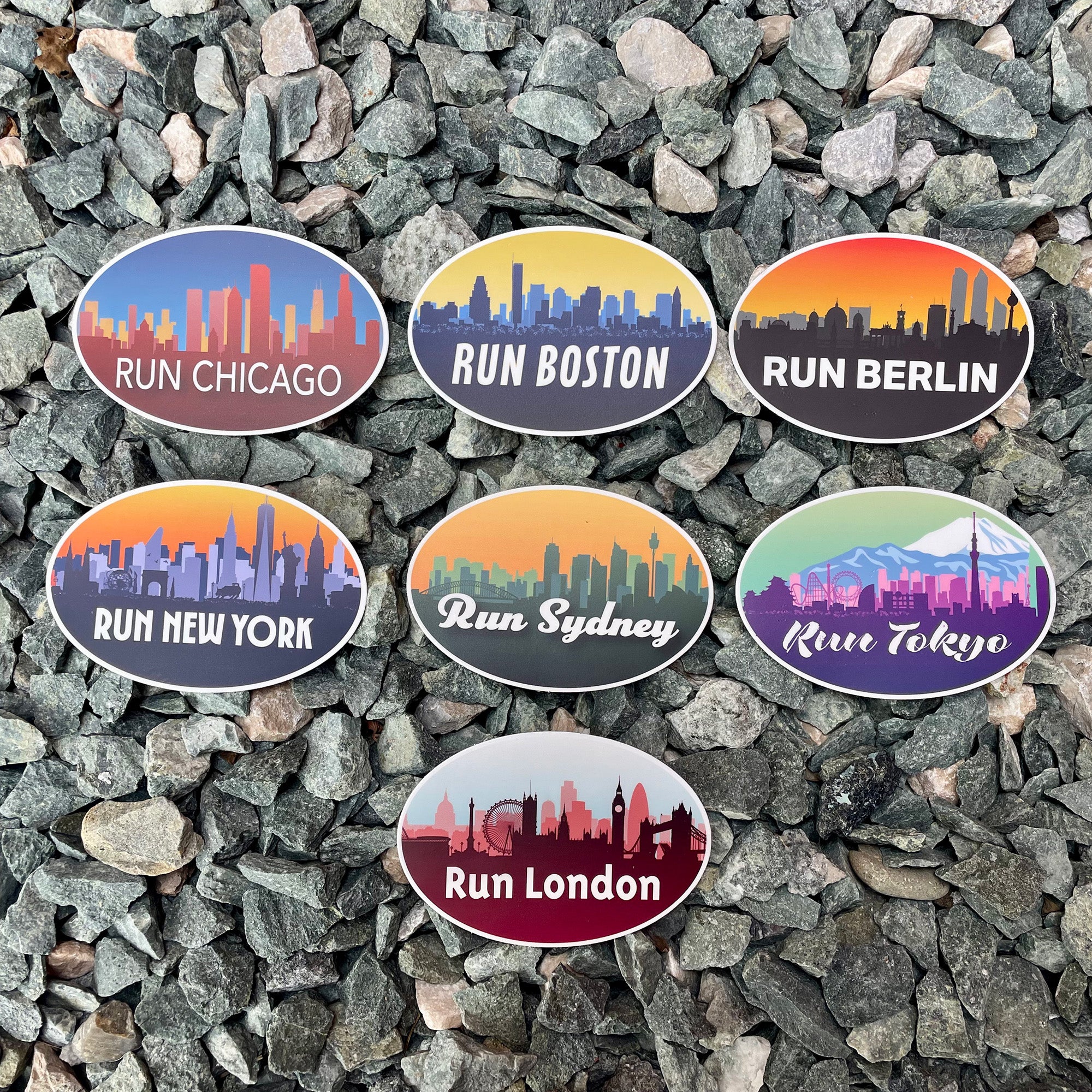 Set of oval stickers with city names and skyline designs on a gravel background